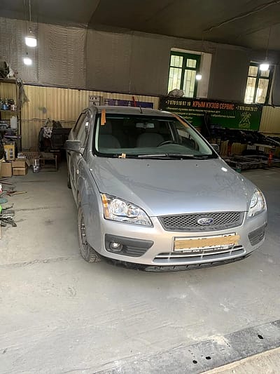 Ford Focus после ремонта в цехе, на фоне вывески мастерской