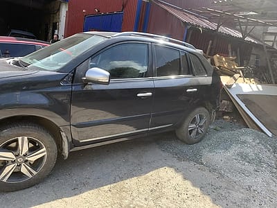 Тёмный кроссовер Renault после ремонта и покраски левой стороны, во дворе цеха