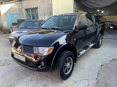 Чёрный пикап Mitsubishi L200 после ремонта, во дворе цеха